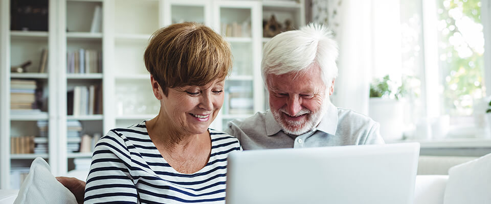 Couple de personnes âgées comparant différentes options de prêt sur valeur nette immobilière et de prêt inversé pour les aider à faire des économies.