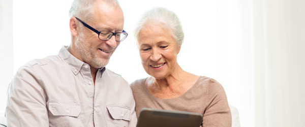 Couple d’aînés canadiens à la maison avec une tablette, cherchant à en savoir plus sur les hypothèques inversées